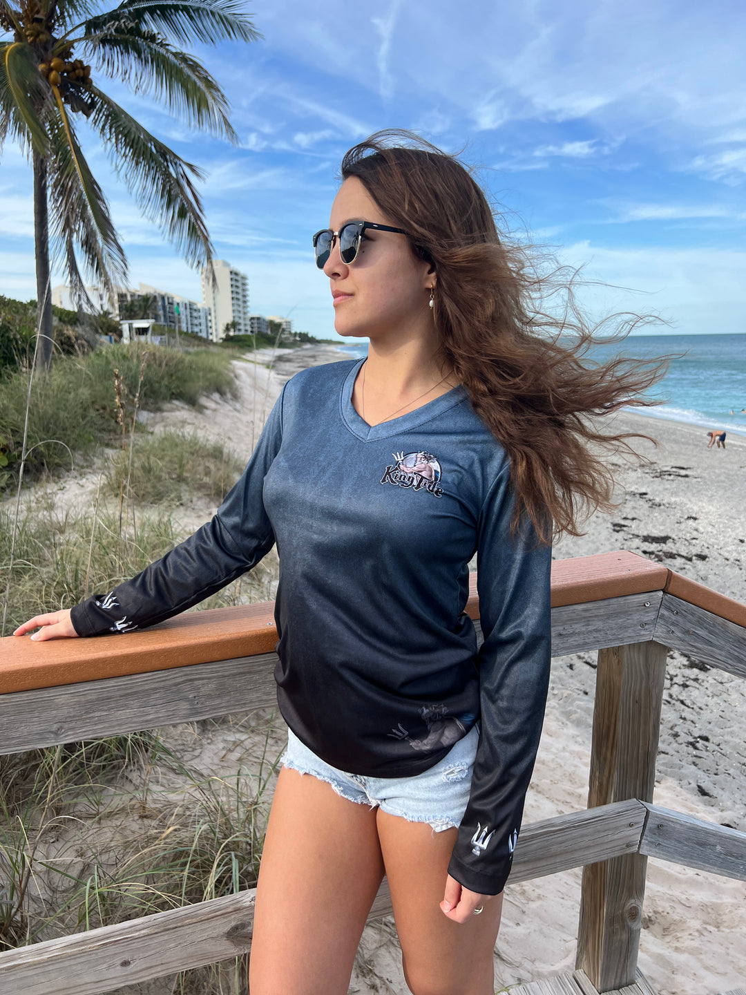 King Tide long sleeve performance shirt in serene black.  Front side showing King Tide logo on left chest and tridents on the sleeves at wrists. King Tide ghost is on bottom left front. UPF50 XS-2X Made in USA. Original art and design by Tal Willis.