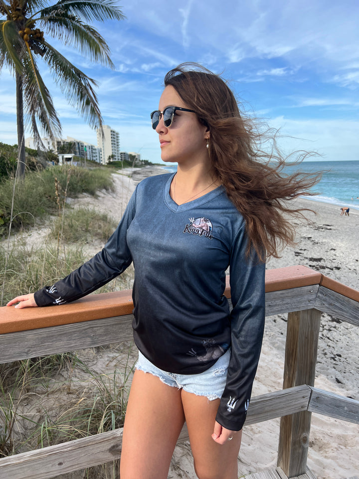 King Tide long sleeve performance shirt in serene black.  Front side showing King Tide logo on left chest and tridents on the sleeves at wrists. King Tide ghost is on bottom left front. UPF50 XS-2X Made in USA. Original art and design by Tal Willis.