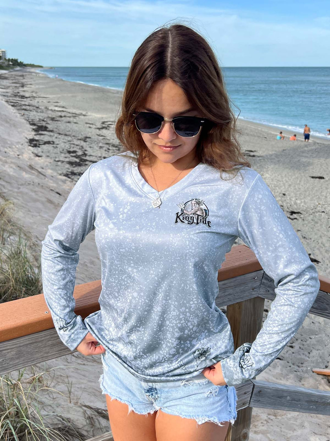 King Tide long sleeve performance shirt with slate fossil print.  Front side showing V Neck, King Tide logo on left chest and tridents on the sleeves at wrists. King Tide ghost is on bottom left front. UPF50 XS-2X Made in USA. Original art and design by Tal Willis.
