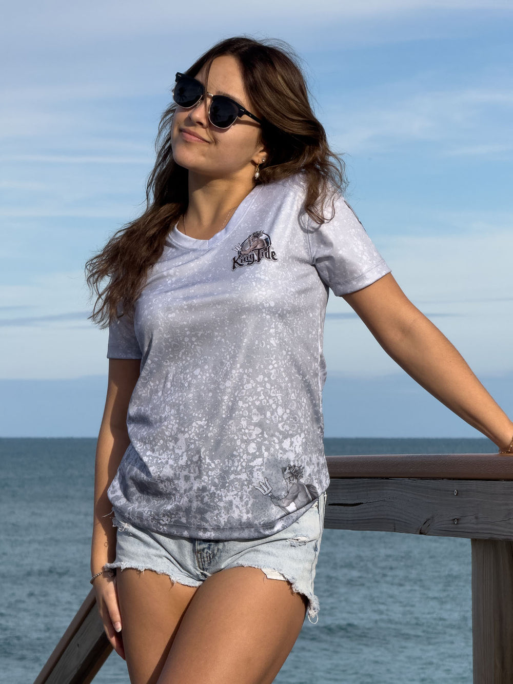 Short Sleeve V neck performance shirt with slate fossil allover print.  Front showing King Tide logo on left chest and ghost King Tide on bottom left. UPF 50. XS-4X. Made in USA. Original art and design by Tal Willis